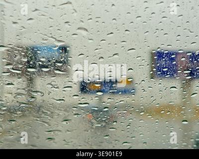 a view through a window covered in raindrops, during a storm or rainy day, The water droplets on the glass obscure the view, creating a blurred effect Stock Photo