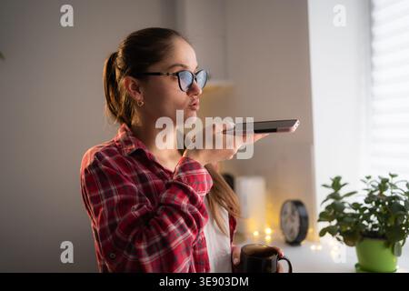 woman using mobile phone apps record audio message or voicemail at home Stock Photo