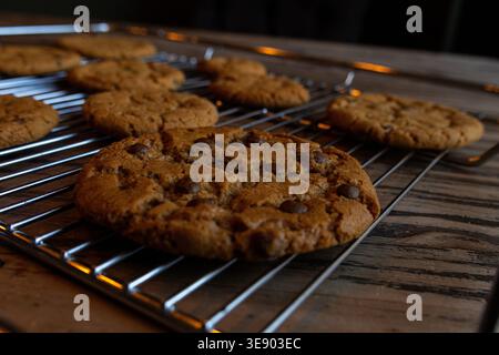 Freshly baked chocolate chip cookies cooling on rack on rustic wooden table Stock Photo