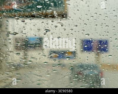 a view through a window covered in raindrops, during a storm or rainy day, The water droplets on the glass obscure the view, creating a blurred effect Stock Photo