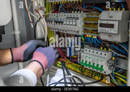 Close up of electrician hands installing and repairing electrical panel with circuit breakers. Professional maintenance of electrical system in a buil Stock Photo
