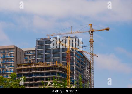 View of two yellow tower cranes and unfinished building construction Stock Photo