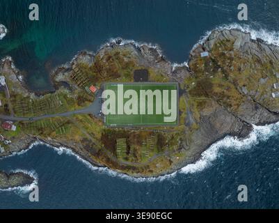 Aerial view of the Henningsvaer Football Stadium on a rocky island surrounded by the dark blue waters of the Norwegian Sea in Henningsvaer, Nordland, Stock Photo