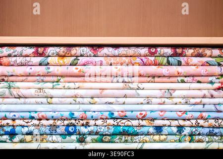 Stacked colorful floral fabrics on shelf with copy space for sewing and retail themes. Stock Photo