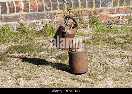 Rusty iron weights hanging from a chain, creating balance for a windmill in Mecklenburg West Pomerania, Germany Stock Photo
