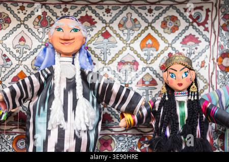 Bukhara, Uzbekistan - March 27, 2024: Handmade Uzbek hand puppets for sale are in tourist shop in old town of Bukhara. Old woman and beautiful princes Stock Photo
