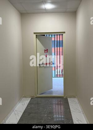 Emergency exit in modern building hallway with marble floor and barred window view in urban setting. Mobile photo Stock Photo
