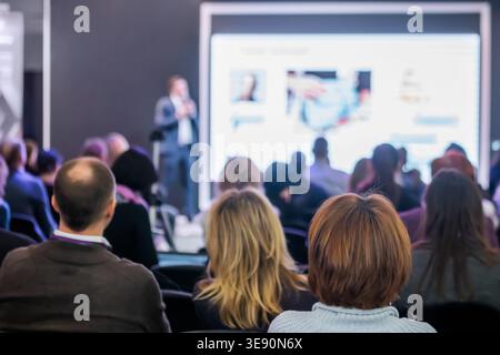 Back view of audience listening presentation at conference hall Stock Photo