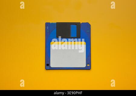 Blue floppy disk centered on yellow background Stock Photo