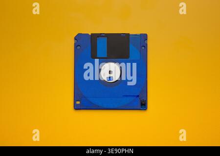 Blue floppy disk centered on yellow background Stock Photo
