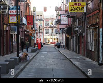 San Francisco, United States - October 3, 2025 - Pedestrians walking through a vibrant, narrow street in Chinatown, surrounded by historic brick archi Stock Photo