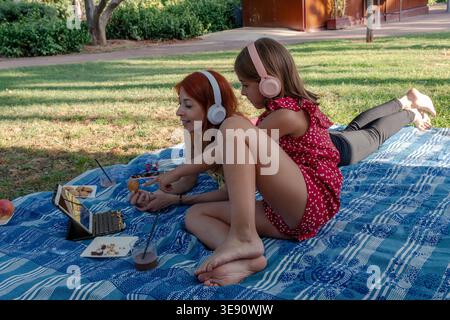 Mother and daughter enjoying picnic using digital tablet Stock Photo