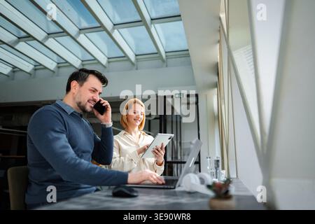 Business colleagues collaborating using technology in modern office space Stock Photo