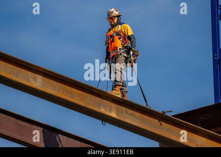 Ironworker standing on a steel beam during construction of a building project in downtown Raleigh, illustrating skilled labor and urban development. Stock Photo