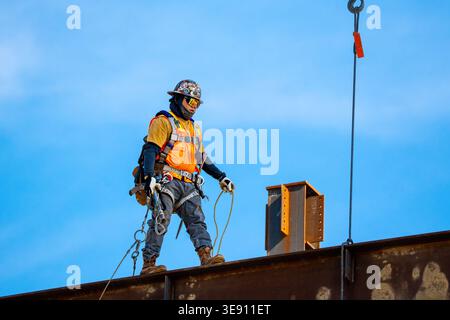 Ironworker standing on a steel beam during construction of a building project in downtown Raleigh, illustrating skilled labor and urban development. Stock Photo