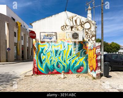 Colorful graffiti mural on a white building wall with an air conditioner and an Algarve sign in Lagos Portugal Stock Photo