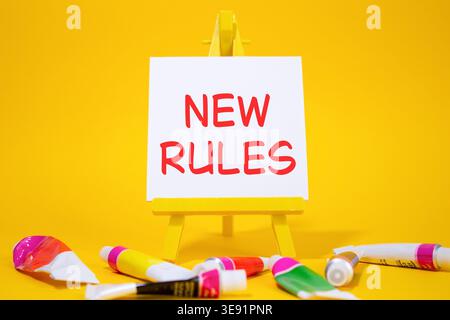 New rules symbol. Concept word Manage stress on wooden blocks. Beautiful yellow background with paints and easel. Business and New rules concept. Copy Stock Photo