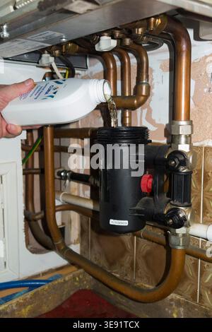 Gas engineer correcting pH balance with inhibitor against corrosion during heating Combi boiler annual service and gas safety test for a landlord in a rental house property. Gas Safe technician / Which? Trusted Trader. (148) Stock Photo