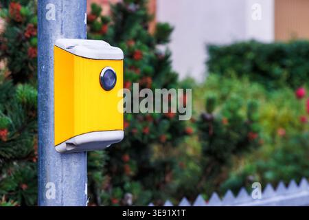 Close up of a yellow pedestrian crossing push button mounted on a pole. Urban street infrastructure Stock Photo