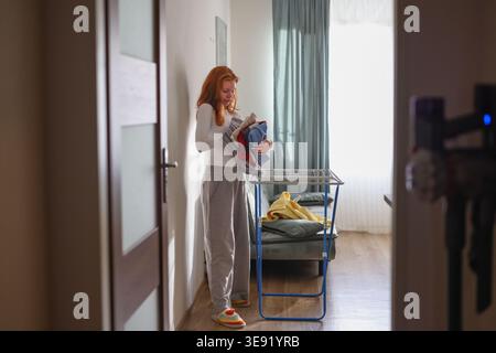 Woman hanging fresh laundry on drying rack at home concept of domestic chores and clean living lifestyle Stock Photo
