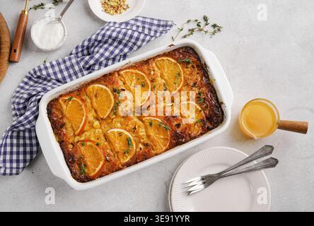 Traditional Greek filo pastry pie with oranges and thyme on white table with white plate and blue napkin, Portokalopita .top veiw. Stock Photo