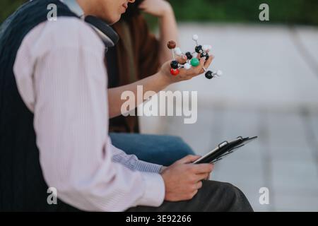 Two students examining a molecular model while studying chemistry together on campus Stock Photo