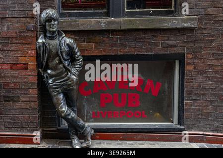 Exterior view of The Cavern Pub on Mathew Street, Liverpool, featuring the iconic bronze statue of John Lennon leaning against the brick Wall of Fame. Stock Photo