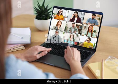 Woman having video chat with her coworkers via laptop at home, closeup Stock Photo