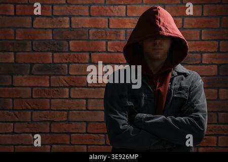 Anonymous man with pixelated face in hoodie near brick wall Stock Photo