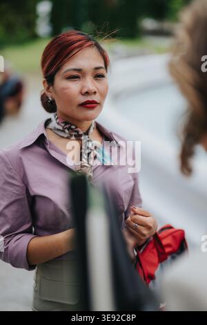 Professional woman in purple blouse engaged in a business conversation outdoors wearing a scarf Stock Photo