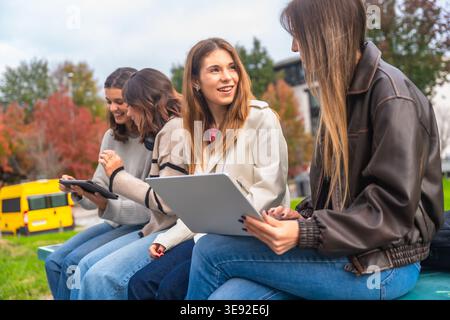 Female students collaborating outdoors using digital devices for education Stock Photo