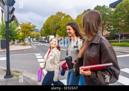 Group of young female friends walking city crosswalk Stock Photo