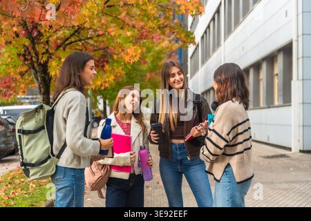 Female students chatting outdoors on university campus in autumn Stock Photo