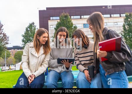 Students group sitting outdoors using tablet on campus Stock Photo