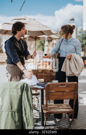 Business colleagues having a discussion over documents during an outdoor cafe meeting Stock Photo
