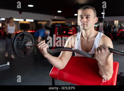 Young man training with barbell in gym Stock Photo