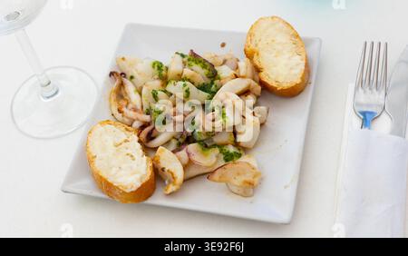 Grilled calamari and two pieces of bread served in a plate Stock Photo