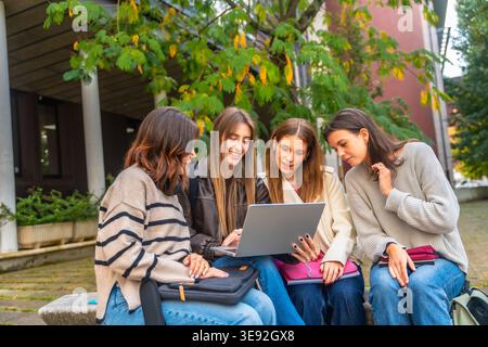 Group of young women collaborating on laptop for university project Stock Photo