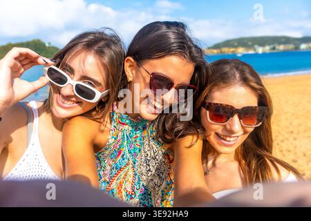 Three young women smiling taking beach selfie Stock Photo