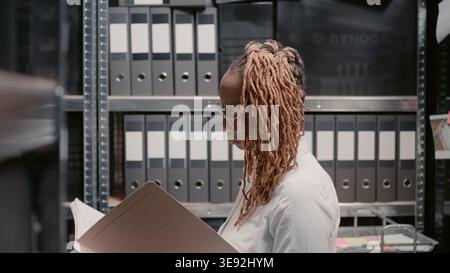Police investigator reading witness statements, looking at surveillance footage on archive folders. Female private detective studying information file and searching crime solving insight. Stock Photo