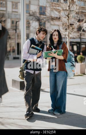 Two college students studying together on a sunny urban campus while taking notes and discussing Stock Photo