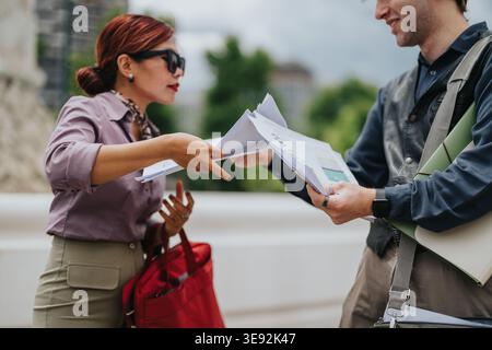 Business professionals exchanging documents outdoors during a casual street meeting Stock Photo