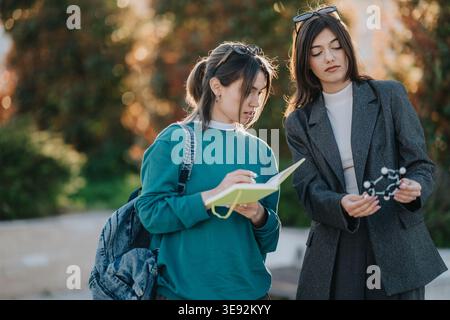 Two students studying a molecular model outdoors on campus while taking notes and discussing science Stock Photo
