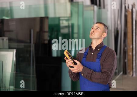 Worker using remote control to operate machinery in glass workshop Stock Photo