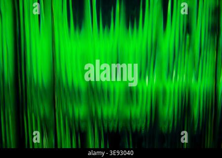 Abstract bright green vertical glowing neon light waves through corrugated glass texture Stock Photo