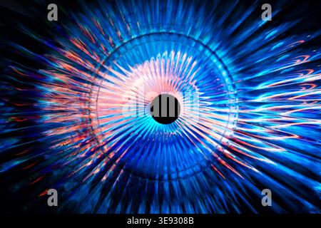 Circular abstract burst of bright blue and orange radiating neon rays forming an eye Stock Photo