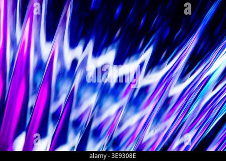 Waves of vibrant blue and purple light on a textured metallic surface with reflective ripples Stock Photo