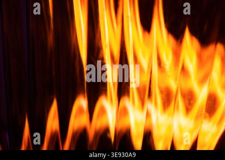 Abstract glowing orange light waves resembling burning fire flames on a dark background Stock Photo