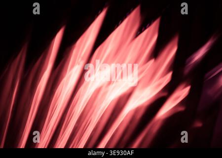 Soft glowing pink and red light streaks radiating diagonally across a dark background Stock Photo