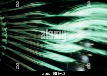 Abstract green glowing wavy light trails on a dark black background Stock Photo